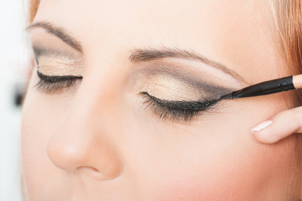 Woman applying an eyeliner. 