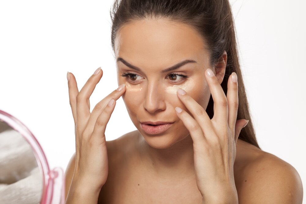 Woman applying a primer on her face. 