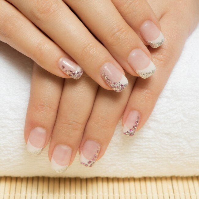 Woman with a glittery French manicure.