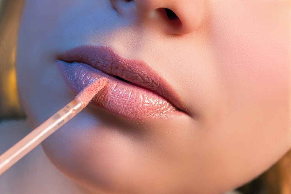 Woman applying lip gloss. 